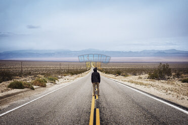 rear-view-of-man-standing-on-empty-highway-looking-towards-horizon-CAVF18263.jpg